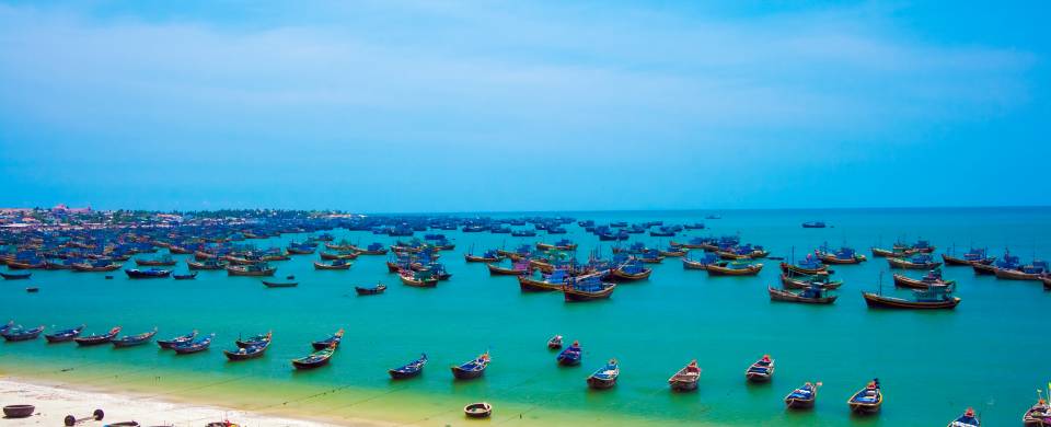 Hundreds of fishing boats floating on the turquoise water in Mui Ne