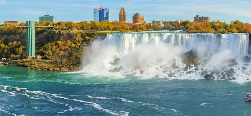 Panorama of the mighty Niagara Falls with a cruise boat getting close to the cascade