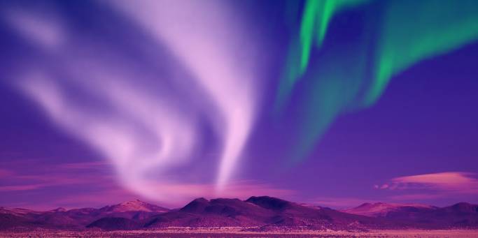 Vivid display of the Northern Lights against a purple sky