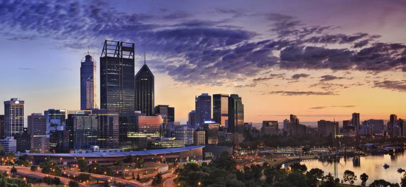 Wide sunrise panorama of Perth CBD cityscape with swan river reflecting warm yellow sun light from e