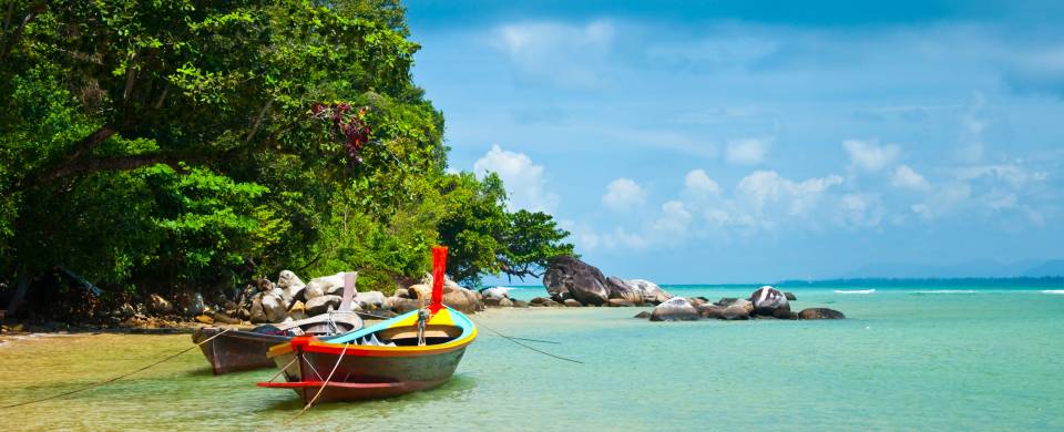 Traditional Thai boats rest in the clear waters of Phuket island