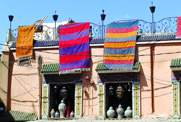 handmade rugs draped over a Moroccan building.