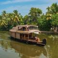 Boat sailing along the river, fringed with thick jungle, in Alleppey