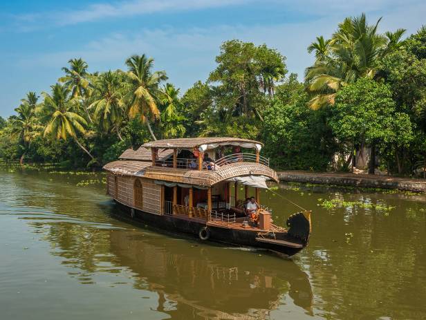 Boat sailing along the river, fringed with thick jungle, in Alleppey