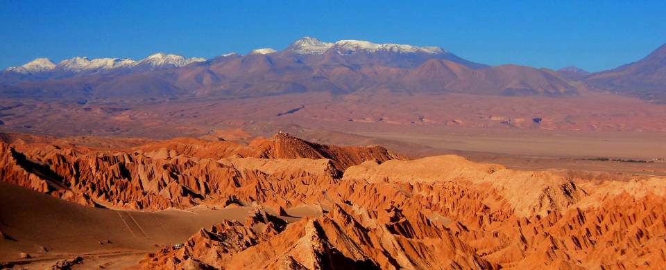 Desert, moonlike landscape of red, rugged rocks and mountains in the background