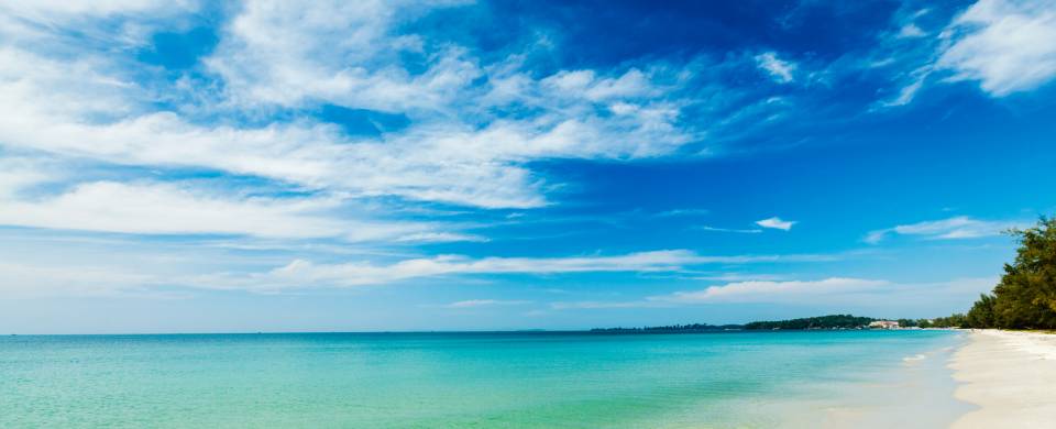 Clouds swirling in the blue sky over the white powder sand and turquoise sea in Sihanoukville