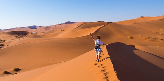A solo female walks along the top of a sand dune | Namibia