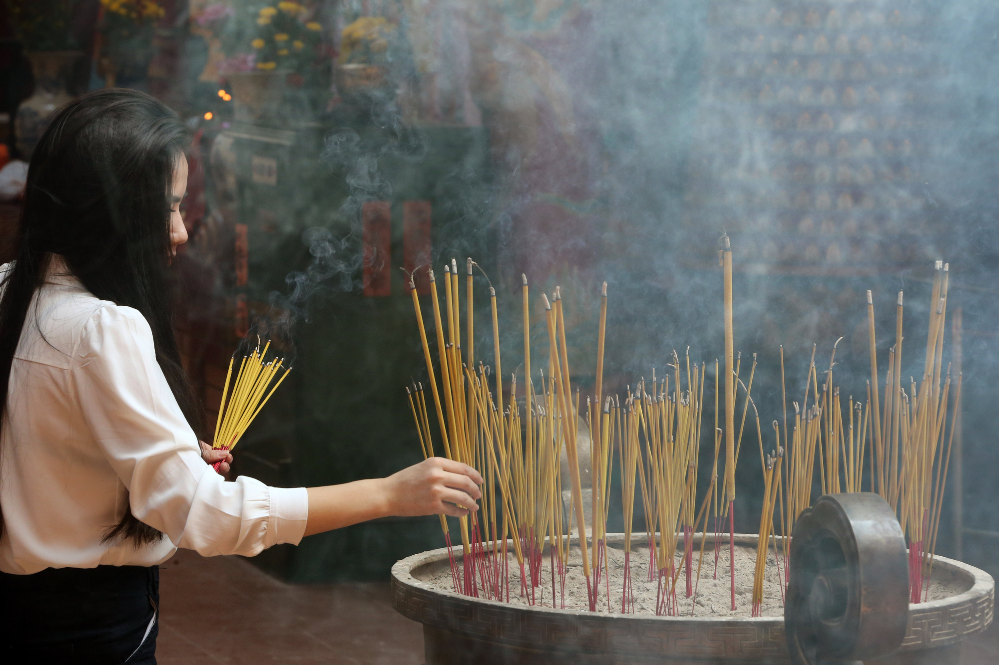 A woman burning incense at a temple