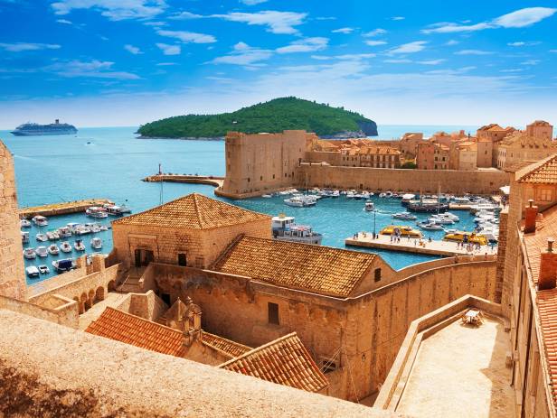 Aerial view of Dubrovnik, surrounded by water and filled with terracotta-roofed buildings